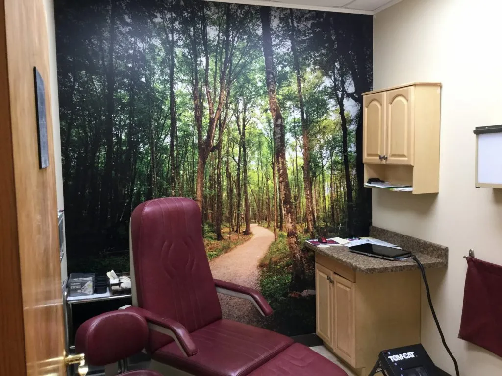 Ronkonkoma NY Podiatry Interior photo: Relaxing patient chair in treatment room with forest road photo mural